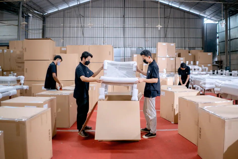 Staff in a warehouse packing furniture into cartons