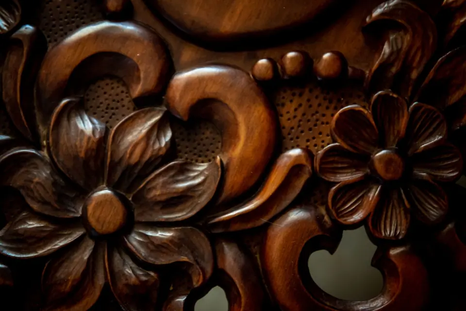 Close view of a carved floral relief in dark wood